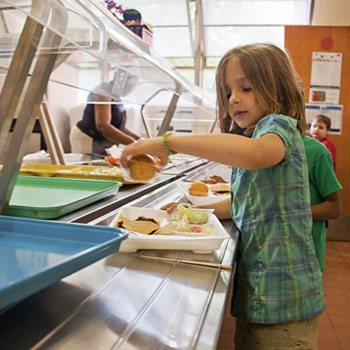 immagine di una bambina che sceglie da mangiare alla mensa della scuola