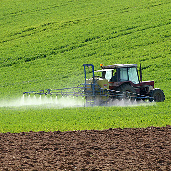 immagine di un trattore che sparge prodotti fitosanitari in un campo coltivato
