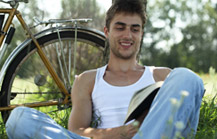 L'immagine rappresenta un giovane in un parco, accanto a una bicicletta