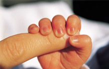 foto della mano di un neonato che stringe il dito di un adulto