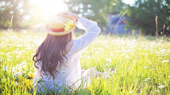 donna con cappello sul prato al sole