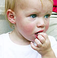immagine di un bambino che si sta mettendo qualcosa in bocca