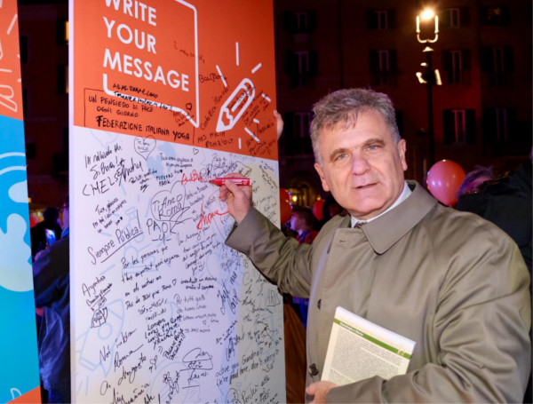 Il sottosegretario alla salute Armando Bartolazzi mentre firma il poster dell'evento 