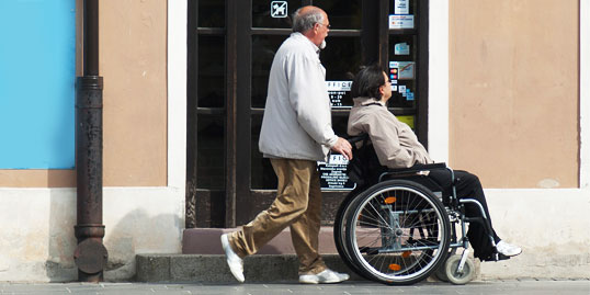 immagine di una persona che fornisce assistenza a una donna in sedia a rotelle