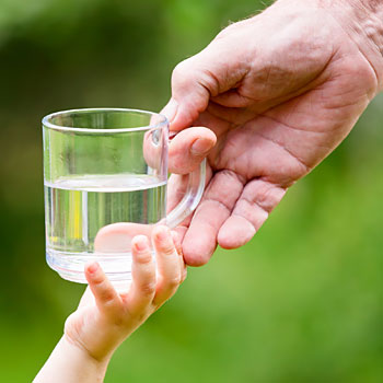 immagine di una mano adulta che porge un bicchiere d'acqua a una mano di bambino