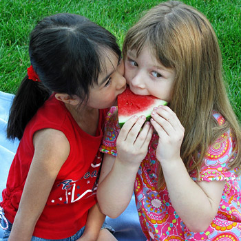 immagine di due bambine che mangiano una fetta di anguria