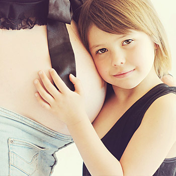 immagine di una bambina che tocca la pancia della mamma incinta