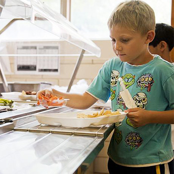 immagine di un bambino che si prepara un piatto alla mensa scolastica