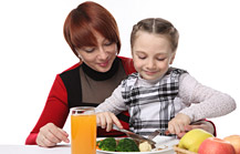 Immagine che rappresenta una bambina che mangia frutta e verdura assieme alla mamma