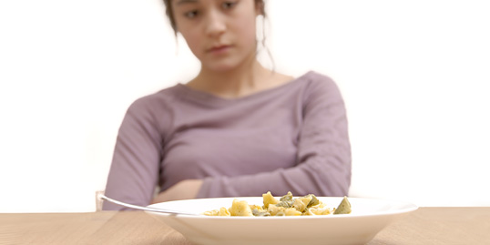 immagine di un'adolescente che rifiuta un piatto di pasta