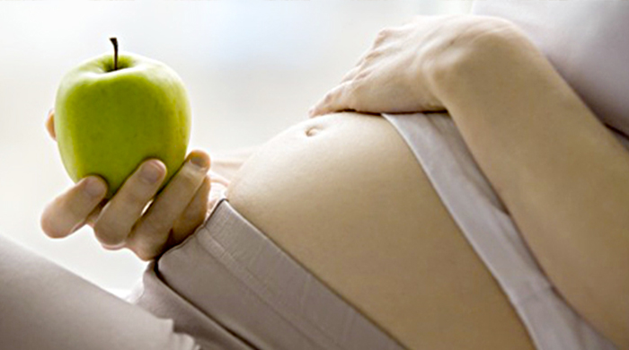 Immagine di donna in gravidanza con una mela