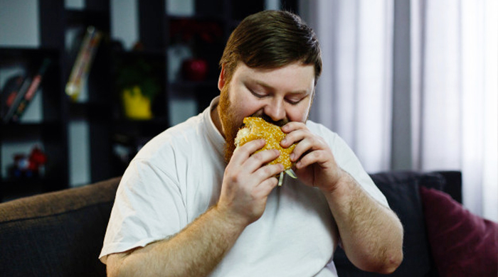 Immagine di una persona in sovrappeso che mangia